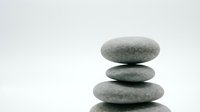Stacked smooth gray stones balanced in zen tower formation on white background, isolated for wellness and meditation design projects.