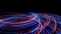 Abstract light trails creating dynamic flowing curves and spirals in blue, purple and orange colors against black background for modern digital designs.