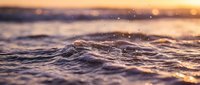 Ocean waves at golden hour sunset with warm light reflecting on water surface creating peaceful seascape atmosphere for relaxation and meditation backgrounds.