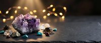 Amethyst crystal cluster with healing gemstones on dark slate, glowing bokeh lights in background, spiritual wellness and meditation concept.