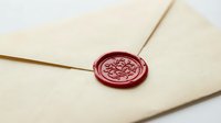 Closed cream envelope with burgundy wax seal featuring ornate floral design, representing official correspondence, authentication, luxury invitations, and formal communication.