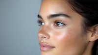 Young woman with natural glowing skin and minimal makeup looking away with soft lighting for beauty and skincare concepts.