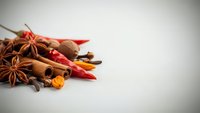 Aromatic spices including star anise, cinnamon sticks, red chili peppers, and turmeric arranged on white background for culinary and cooking projects.