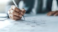 Close up of hand drawing mind map or business strategy diagram on white paper, showing creative planning process and strategic thinking approach.