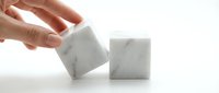 Hand reaching for white marble cube blocks on clean surface for modern minimalist design and architectural concept projects.