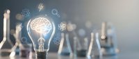 Light bulb with glowing brain inside surrounded by innovation icons and scientific glassware on blurred laboratory background for creative thinking concepts.