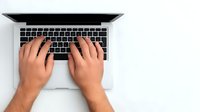 Hands typing on laptop keyboard from above view showing modern workspace and digital productivity for business and remote work applications.
