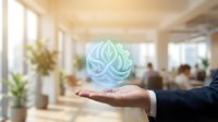 Young male professional in business attire holding glowing blue-green lotus flower hologram above open palm in modern office environment with blurred colleagues and plants.