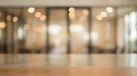 Blurred modern office lobby with wooden floor and glass partitions, suitable for corporate backgrounds and business presentations.