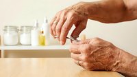 Senior hands opening medicine bottle with pills in modern bathroom setting for healthcare and medication management at home.