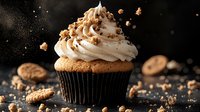 Gourmet cupcake topped with swirled vanilla buttercream frosting and crushed cookies on dark background with falling crumbs and dramatic lighting.