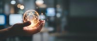 Hand holding glowing light bulb with network connections in modern office environment representing innovation, creativity and business solutions.