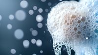 Foamy soap bubbles with sparkling water droplets creating luxurious cleansing texture for skincare and hygiene product advertisements.