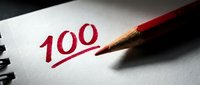 Red pencil marking perfect score of 100 on white paper with underline, symbolizing academic excellence, achievement and success in education.