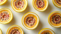 Fresh halved citrus fruits showing vibrant pink flesh and yellow rind arranged in geometric pattern on light background, creating modern minimalist food composition.