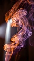 Colorful swirling smoke in orange and purple tones rises against a dark background with a dramatic light beam, creating an abstract art effect.