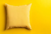 Soft yellow cushion pillow on vibrant yellow background with shadow. Clean minimal composition for home decor and interior design concepts.