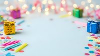 Colorful birthday party celebration background with gift boxes, confetti and bokeh lights creating festive atmosphere for greeting cards and invitations.