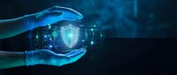 Hands holding glowing shield symbol with digital network interface, representing cybersecurity protection and data safety technology solutions.