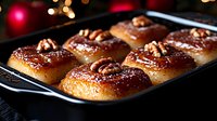 Freshly baked sticky buns with pecans and caramel glaze arranged in baking pan. Golden brown dough topped with nuts creates appetizing breakfast pastry.