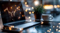 Laptop displaying financial chart with coffee cup on desk against blurred bokeh lights background creates cozy evening work atmosphere. For business concepts.