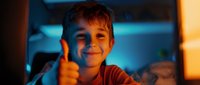 Young Caucasian boy showing thumbs up gesture with confident smile in dramatic blue and orange lighting, expressing positivity and approval in cinematic style.