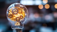 Light bulb with golden gears inside representing innovation, creativity and mechanical thinking against blurred bokeh background for business concepts.