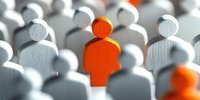 Standing out from crowd concept with orange figure among grey figures, selective focus on leadership and individuality representation for business success.
