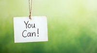 Motivational white paper tag hanging on rope with You Can text against soft green blurred background for inspiration and encouragement concepts.