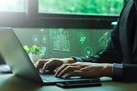 Professional businessman hands typing on laptop with green holographic smart home automation icons floating above screen for sustainable technology solutions.