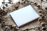 White blank square mockup on natural burlap texture with dried floral branches, creating rustic composition for product presentation and branding.