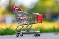 Empty red shopping cart on blurred outdoor background for retail and consumer concepts.