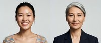 Young Asian businesswoman and mature colleague smiling confidently in professional attire against neutral background for corporate presentations.