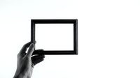 Black empty picture frame held by hand against white background for mockup design and presentation projects.