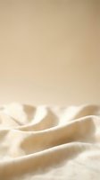 Soft beige fabric with gentle folds and waves creating elegant textile background with warm neutral tones and smooth texture for luxury design projects.