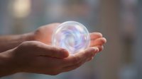 Hands holding glowing energy sphere with swirling light effects for spiritual healing meditation and wellness concepts in soft bokeh background.