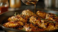 Juicy glazed chicken thighs with honey and sesame seeds in cast iron pan. Golden sauce drizzling over perfectly caramelized meat creates appetizing food photography for restaurant menu.