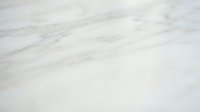 White marble surface with natural veining and subtle gray streaks, suitable for backgrounds, interior design projects, and luxury product photography.