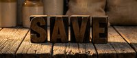 Wooden letterpress blocks spelling SAVE on rustic table surface with burlap sacks in background. Financial planning and money saving concept for business.