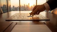 Executive placing final puzzle piece on board with city skyline at sunset through office windows, symbolizing business strategy, problem-solving, and corporate success.