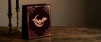 Ancient spellbook with glowing dragon symbol and ornate corners on wooden table beside candlesticks for fantasy gaming and mystical storytelling projects.