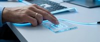Man's hand touching glowing transparent device with 5G symbol on desk, futuristic technology concept for connectivity and wireless communication.