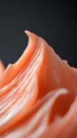 Macro abstract view of coral pink waves with soft flowing curves and delicate texture against dark background, creating organic minimalist composition.
