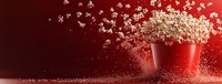 Popcorn explosion from red bucket on dark red background with flying kernels creating dynamic motion effect for entertainment and movie concepts.