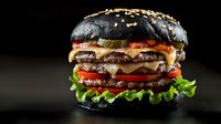 Juicy black burger with melted cheese, fresh vegetables, and beef patties on dark background. Gourmet fast food with charcoal bun and sesame seeds.