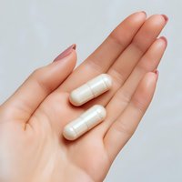 White medical capsules on female palm with natural manicure against light background, healthcare and pharmaceutical concept for medical designs.