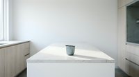 Minimalist white marble countertop with single metal cup in empty bright room with natural light, suitable for interior design and lifestyle projects.