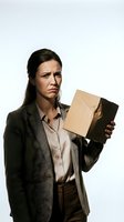 Frustrated businesswoman holding empty cardboard box with disappointed expression, wearing blazer and button-up shirt against white background for business failure concepts.