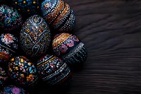 Intricately decorated black Easter eggs with colorful folk art patterns featuring dots, swirls and floral motifs on dark wooden background. Traditional holiday design.