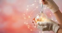 Woman in beige sweater holding glowing light bulb with network connections on pink background representing innovation and creative ideas for business.